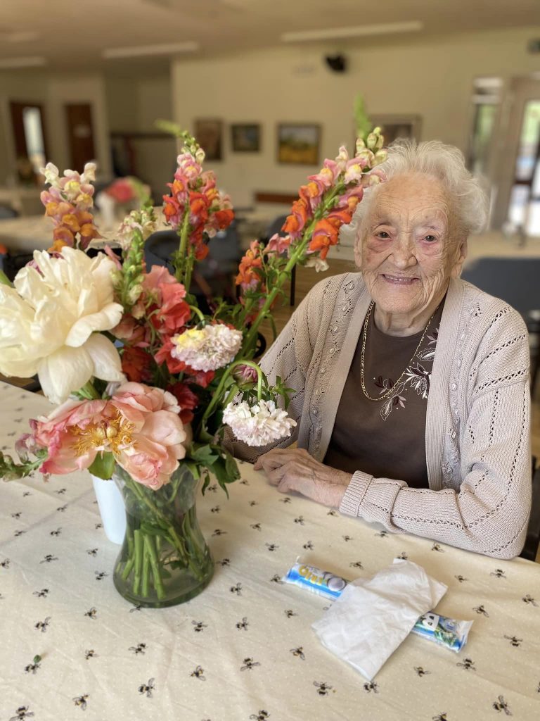 elderly lady enjoying flowers at nursing home 